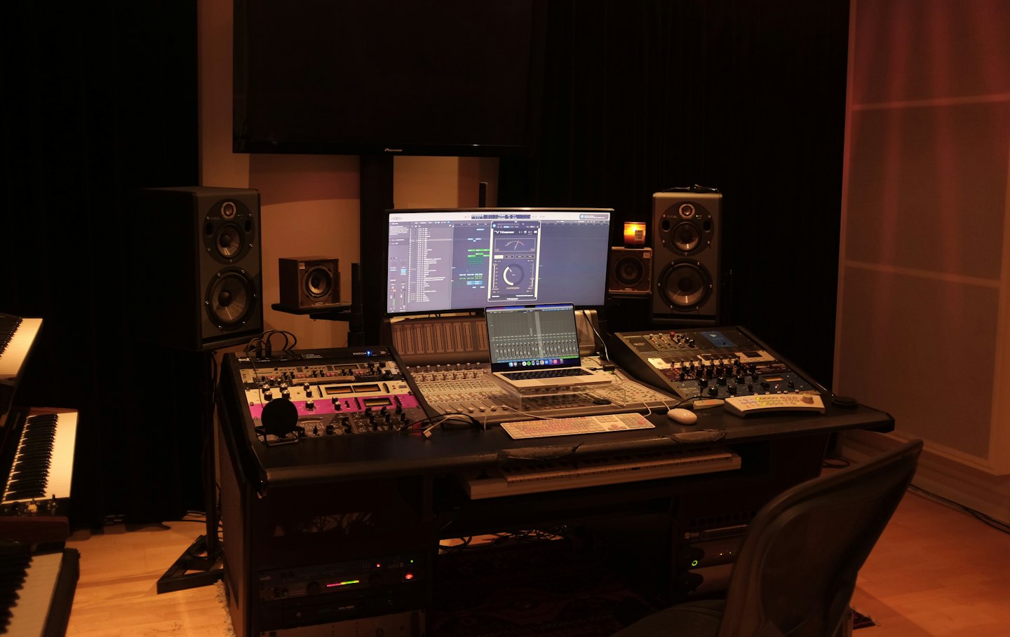 Un moderno escritorio de estudio de grabación musical con equipo de audio y computadoras.